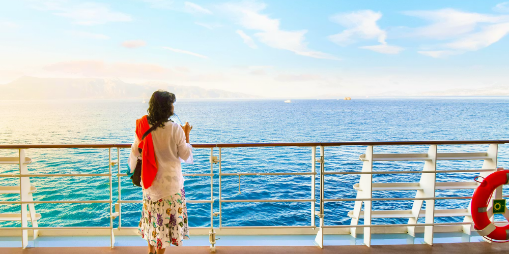 Solo traveler enjoying a peaceful luxury cruise balcony view overlooking the open ocean at sunset, highlighting upscale solo cruise vacations and relaxing sea travel experiences.
